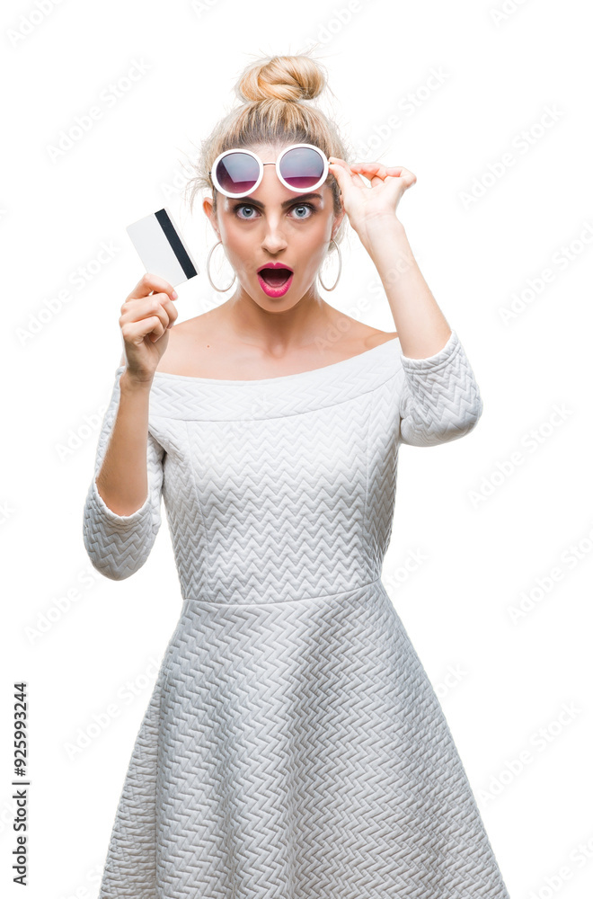 Canvas Prints Young beautiful blonde woman holding credit card over isolated background scared in shock with a surprise face, afraid and excited with fear expression