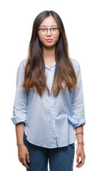 Fototapeta premium Young asian business woman wearing glasses over isolated background with serious expression on face. Simple and natural looking at the camera.