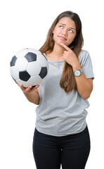 Young beautiful brunette woman holding soccer football ball over isolated background serious face thinking about question, very confused idea