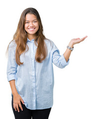 Young beautiful brunette business woman over isolated background smiling cheerful presenting and pointing with palm of hand looking at the camera.