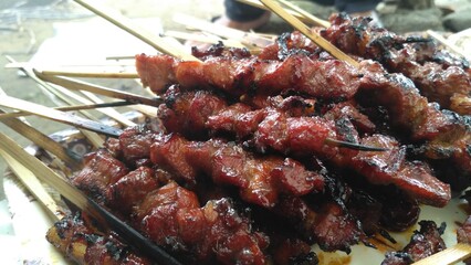 Satay, Indonesian taridtional food. Close-up of deliciously grilled meat skewers, perfectly glazed and charred. A mouth-watering image ideal for food photography, culinary arts, and BBQ themes.
