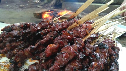 Satay, Indonesian taridtional food. Close-up of deliciously grilled meat skewers, perfectly glazed and charred. A mouth-watering image ideal for food photography, culinary arts, and BBQ themes.