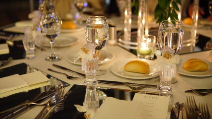 A minimalist and elegant wedding table setting with white plates, mirrored placemats, and a touch...