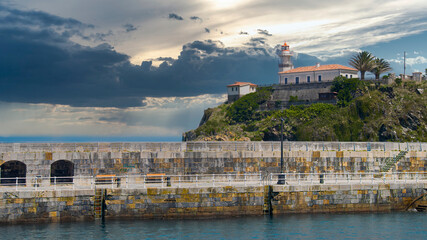 Espigón y faro en el puerto de la villa costera de Cudillero en el litoral del mar Cantábrico, España. Con cielo editado