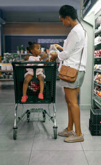 Black family, mother and baby with shopping trolley in cart together at grocery store. African mom with daughter, child or girl in shop carriage for ingredients or commerce at indoor supermarket © SensSai/peopleimages.com