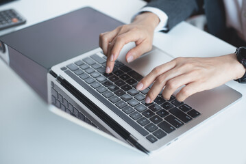 Close up, Business woman hand typing on laptop computer, working at office with digital tablet on office table. Woman searching the information, surfing the internet on laptop