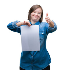 Young adult woman with down syndrome holding blank paper sheet over isolated background happy with...