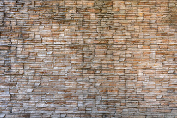 A wall made of stone with a lot of cracks and holes. The wall is brown and gray