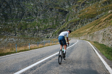 Fototapeta premium Male cyclist during ride a bicycle. Sports motivation image.Good road for cycling. Man cyclist riding a gravel bike with a view of the mountains. Travel biking concept. Transfăgărășan road in Romania.
