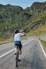 Fototapeta premium Man cyclist in cycling kit and a helmet is drinking water from a sports bottle during training.