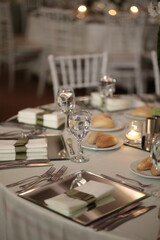 A beautifully decorated wedding table with white flowers, crystal glassware, and candles. The table is set with elegant place settings and a mirrored runner