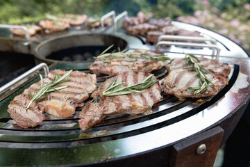 A beef steak from marbled beef seasoned with sprigs of rosemary is cooking on the grill surface. The grill is in the backyard of your chalet. Outdoor cooking. Meat with grill marks. 