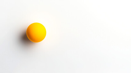 A vibrant yellow ball resting on a clean, white surface, creating a minimalistic and modern aesthetic.