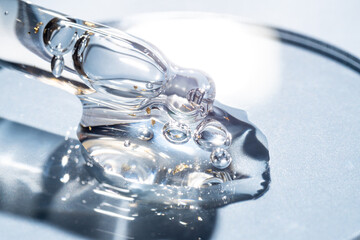 Liquid serum and dropper on a blue background. 24k gold Serum drops in the form of a circle with a pipette.