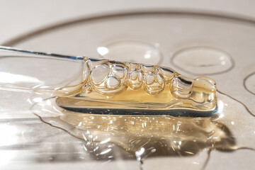 orange beauty face oil dripping from dropper on beige background. Skin care cosmetic advertisement with macro