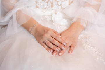 Elegant Bride's Hands Resting Gracefully on Wedding Dress - A Symbol of Love and Serenity on the Special Day
