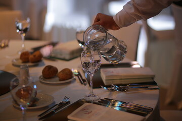 Waiter pouring water into a glass at a fine dining restaurant