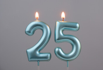 Burning blue birthday candles on gray background, number 25