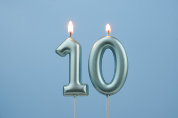 Burning blue birthday candles on blue background, number 10