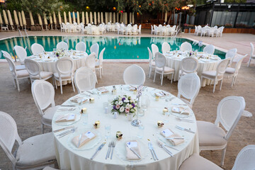 Elegant Poolside Wedding Reception with Round Tables and White Chairs
