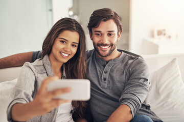 Selfie, happy and couple on sofa in home for social media, online post and profile picture in living room. Dating, love and people hug, embrace and take photo for bonding, relationship and relax