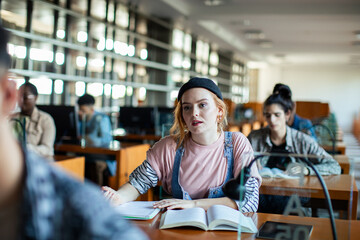 Focused female student taking notes in university library study session