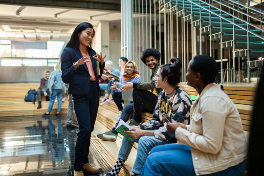 University students having discussion with a professor in modern campus setting