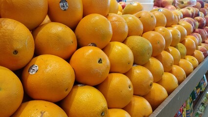 A vibrant pile of fresh mandarin oranges with green leaves, neatly stacked in a market. The bright...