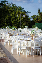 Outdoor Elegant Event by the Pool: A beautifully set round dining table with white chairs and a floral centerpiece, situated next to a swimming pool, perfect for a garden party, wedding