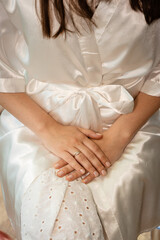 Bridal Preparation Moment: Detailed view of a bride's hands and a beautiful ring, as she wears a comfortable, elegant robe, conveying anticipation and quiet reflection before a special event