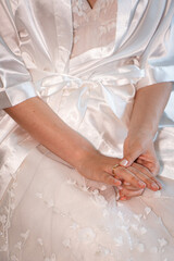 Bridal Preparation Moment: Detailed view of a bride's hands and a beautiful ring, as she wears a comfortable, elegant robe, conveying anticipation and quiet reflection before a special event