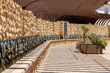 Stone wall fountain with arched wooden pergola