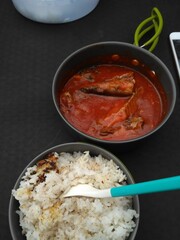 A close-up view of canned sardines immersed in rich tomato sauce. The image captures the texture and detail of the fish and sauce, perfect for illustrating food packaging or recipes.