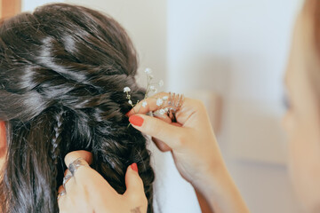 Female hands placing a white flower in the black hair of a woman in bridal headdress