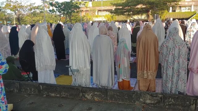 back view women Muslims pray together to celebrate the end of Ramadan at parking area of Epicentrum Mall Lombok.