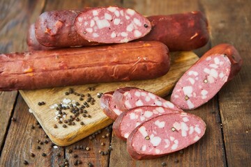 Sausage with lard lies on a wooden surface surrounded by spices. Meat production.