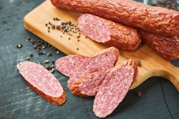 The sausage lies on a wooden surface surrounded by spices. Meat production.