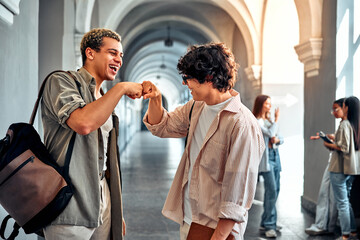 Two friends greet each other at school. Cheerful students met after the holidays.