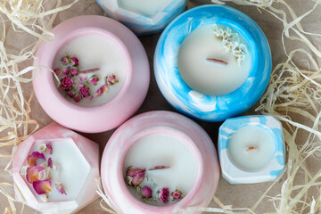 top view of aromatic candles with wooden wick in plaster candlestick, close-up on wrapping paper background, handmade concept