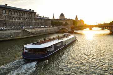 The Seine River in Paris with a historic bridge and the illuminated Eiffel Tower in the background. The calm water reflects the city lights, creating a romantic atmosphere of a Parisian evening