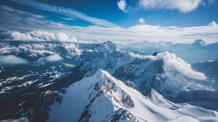 Snowy mountain peaks rise majestically, surrounded by clouds and a vivid blue sky on a clear day