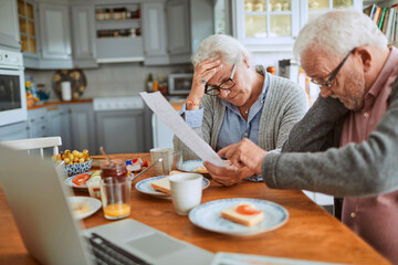 Senior couple reviewing documents together at kitchen table