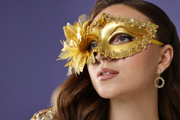 Beautiful woman wearing carnival mask on purple background, closeup. Space for text