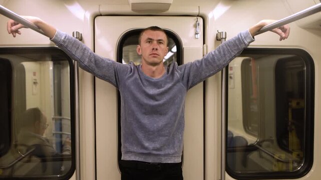 Serious and arrogant looking young man standing in a subway car and stares intently 4K