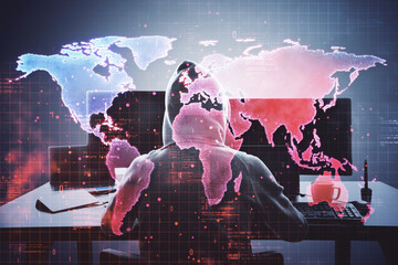 Hacker in hoodie using computer with digital world map overlay, cyber security.