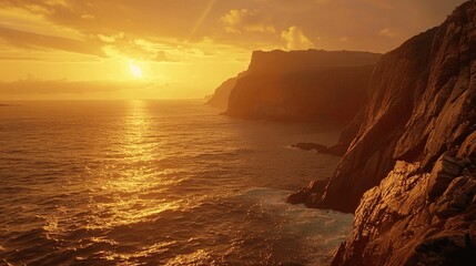 Peaceful coastal cliff at sunset with warm amber light over rugged rocks and the distant horizon.