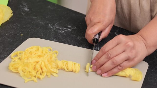 Female Hand Slicing Telur Rawis, Thin Slice Egg Omelete for Nasi Kuning or Nasi Uduk Side Dish Topping 