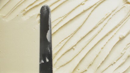 Overhead view of silky smooth buttercream being spread with a spatula, top view of frosting being spread