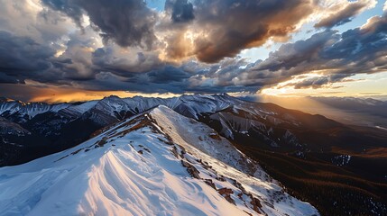 An expansive view of a snow-covered mountain ridge under a dramatic sky filled with dark clouds and sunlight breaking through