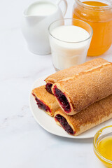 Berry strudel, glass of milk and honey on a light background. Free space for copy. Dessert made from puff pastry and fruit filling.